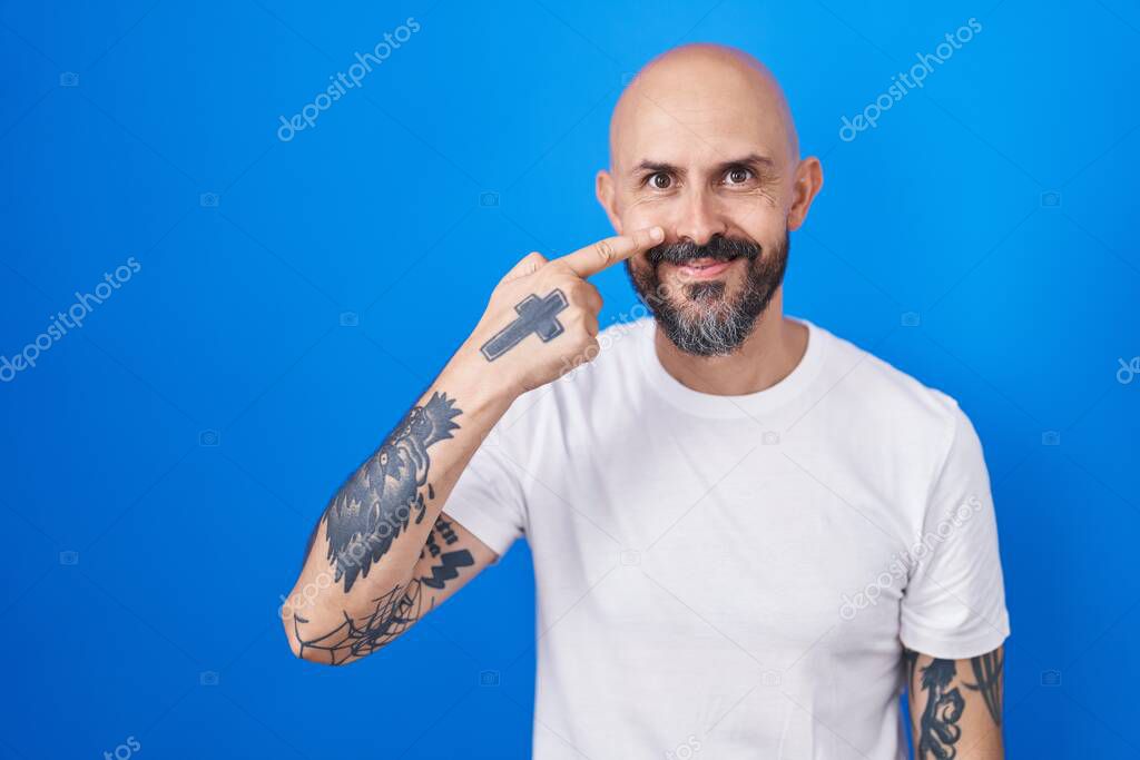 Hombre Hispano Con Tatuajes De Pie Sobre Fondo Azul Se Alando Con La