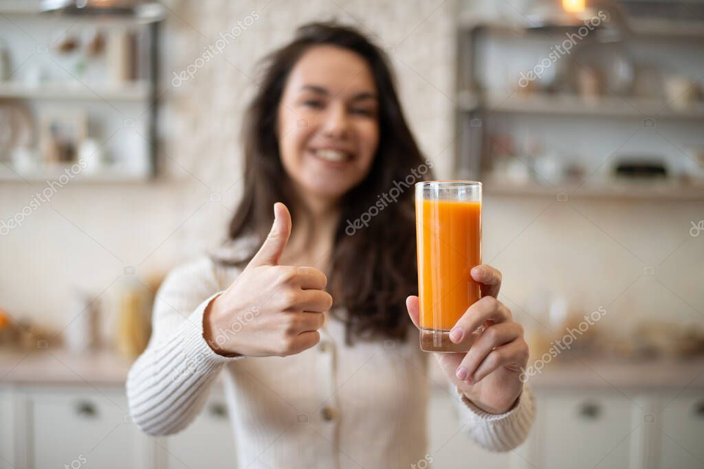 Señora caucásica positiva sosteniendo vaso de jugo de naranja orgánico