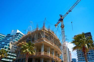 Deniz kenarındaki modern bir binanın inşaat sahasında kule vinci..