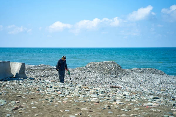一个带着金属探测器的男人正在海滩上寻找度假者丢失的珠宝 格鲁吉亚巴统 2021 — 图库照片