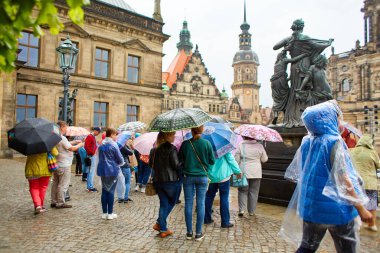 Yağmurda şemsiyeli bir turist kalabalığı anıta bakıyor. Kötü havada bir tur. Dresden, Almanya - 05.20.2019