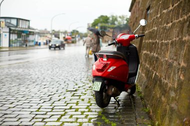 Kırmızı bir scooter yağmur süresince taş bir duvara park edilir. Dresden, Almanya - 05.20.2019