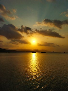 Okyanus kıyısında bulutlu, yakıcı gün batımı.