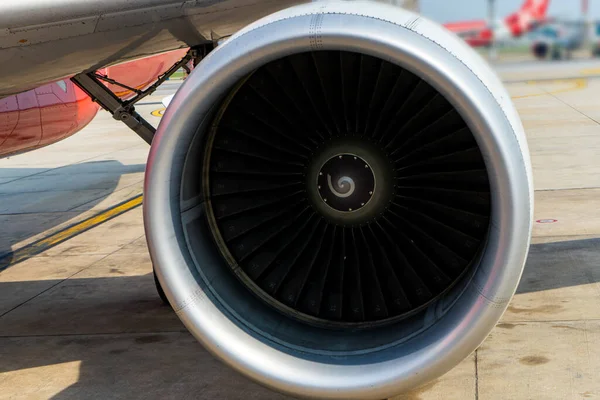 Close-up of a turbine engine of a passenger plane in an airport parking.