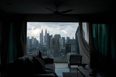 Rüzgar panoramik pencerenin perdesini bir şehir manzarasıyla hışırdatıyor. Kuala Lumpur, Malezya - 06.11.2020