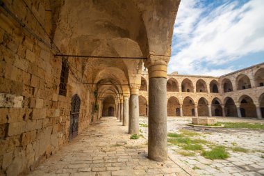 Medieval square building with a courtyard and many arches.