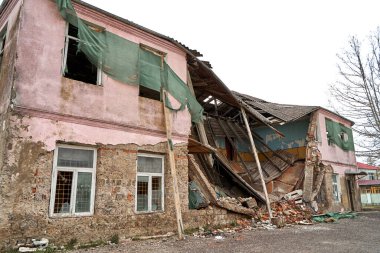 An abandoned two-story building with a crumbling roof.