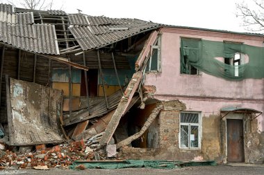 An abandoned two-story building with a crumbling roof.