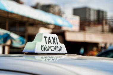 A checkerboard of a Georgian cab in the background of the city.
