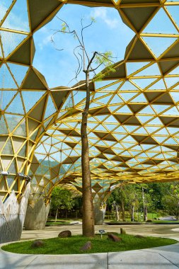 A futuristically designed sunshade with holes for trees in a city recreation park. Kuala Lumpur, Malaysia - 10.31.2022
