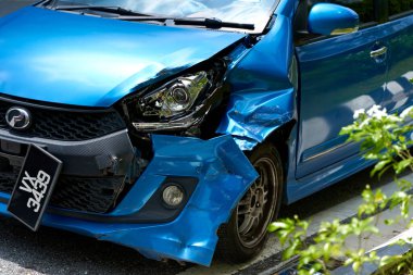 A blue car with a broken headlight and a dented front fender. Kuala Lumpur, Malaysia - 11.09.2022