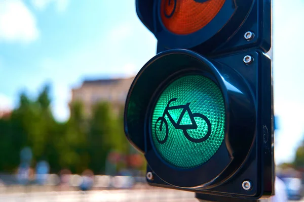 Close-up of a traffic light for cyclists, which is glowing green. A bicycle is shown on the traffic light.