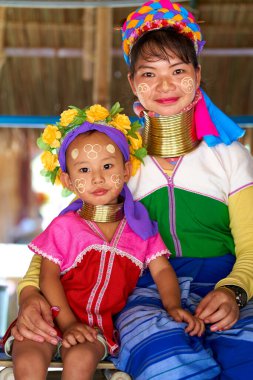 Uzun boyunlu kabileden bir kadın. Boynuna taktığı metal yüzüklerle tanınıyor. Çocuğunu tutuyor. Fotoğraf anne ve çocuk arasındaki bağı yakalar. Chiang Rai, Tayland - 02.09.2023