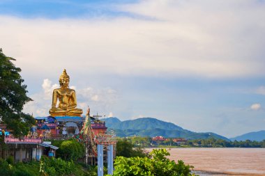 Görkemli altın Buda heykeli açık mavi gökyüzüne dikildi. Heykelin etkileyici boyutu ve zarif ayrıntıları dingin arka planda güzel duruyor. Chiang Rai, Tayland - 02.09.2023