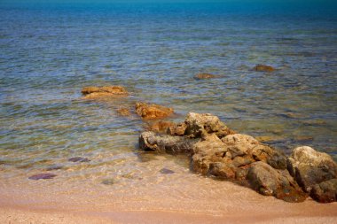 Stones in the sea on a sandy shore. Perfect deserted beach.