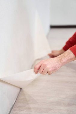 Repair and renovate the interior of the house with their own hands. Close-up of the moment of tearing the old wallpaper off the wall.