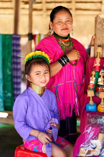 stock image woman from the long-necked tribe, known for the metal rings worn around their necks, holding her child. Photo captures the bond between mother and child and celebrates cultural diversity and tradition. Chiang Rai, Thailand - 09.02.2022