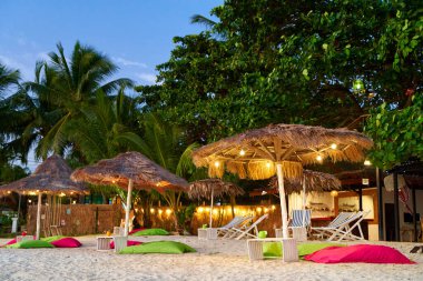 Plaj şemsiyesi tropik bir ada sahilinde kurutulmuş palmiye yapraklarından yapılmıştır. Lüks bir tatil konsepti.