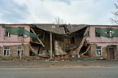 An abandoned two-story building with a crumbling roof.