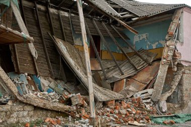An abandoned two-story building with a crumbling roof.