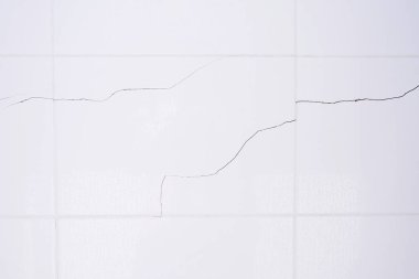 Banyoda su damlacıkları olan beyaz fayanslı bir duvar. Kırık, kırık fayanslar. Deprem sonucu duvar yıkıldı.