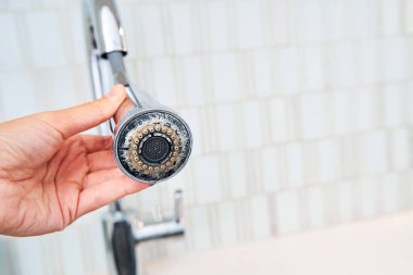 A woman is holding a chrome faucet covered with lime scale clipart