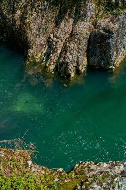The natural pool of the mountain river with emerald clear water.