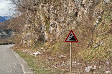 A sign warning of rock falls along a highway in the mountains.