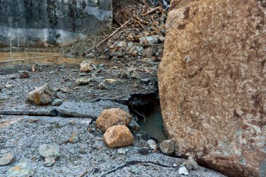 A huge rock fell from the mountains onto the road, destroying the asphalt and blocking half of the roadway.
