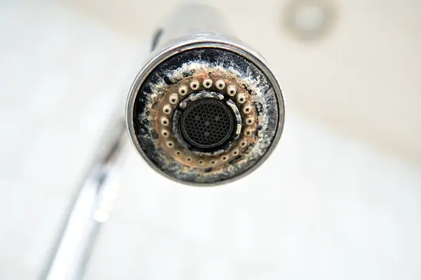 The chrome faucet is covered with lime scale