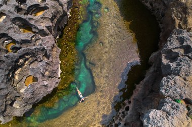 Okyanus dalgası tarafından parçalanmış bir uçurum. Kayanın ortasında doğal gök mavisi banyo havuzu. Endonezya 'nın Nusa Penida adasında popüler bir turizm merkezi.