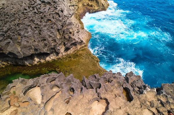 A cliff broken by an ocean wave. The cliff is washed by powerful waves of the ocean. A popular tourist destination Angel\'s Billabong on the island of Nusa Penida in Indonesia