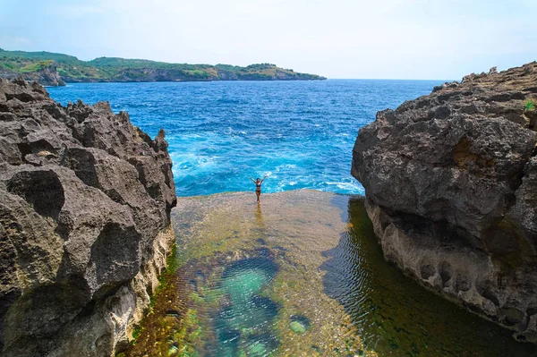 Okyanus dalgası tarafından parçalanmış bir uçurum. Kayanın ortasında doğal gök mavisi banyo havuzu. Endonezya 'nın Nusa Penida adasında popüler bir turizm merkezi.