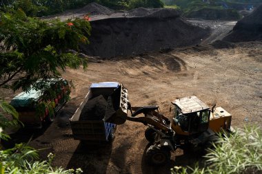 Taş ocağındaki bir traktör mineralleri kamyona yüklüyor.