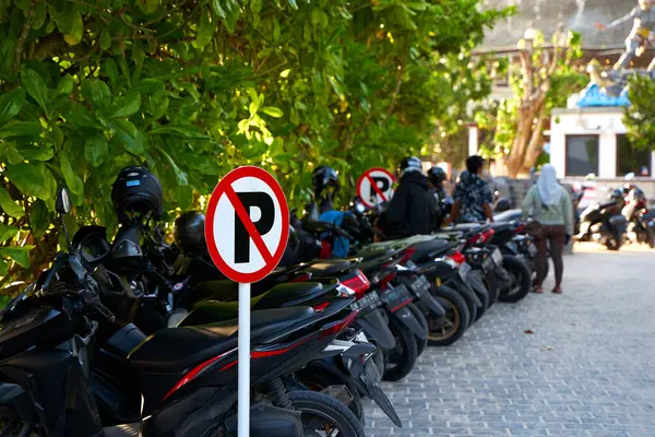 Warning sign - parking is prohibited. Full motorcycle parking near a no parking sign. Bali, Indonesia - 11.30.2022