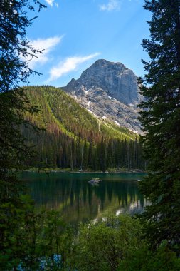 İnanılmaz güzel şeffaf zümrüt göl. Kara Prens Sirk Yolu 'ndaki kayalık dağın yansıması. Güneşli yaz gününde Alberta, Kananaskis 'te kar yağan görkemli Kanada dağları.