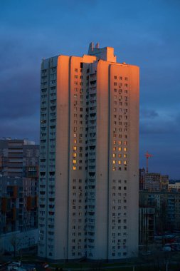 Akşam şehri, gün batımında. Güneş ışınlarıyla aydınlatılmış eski bir panel bina.