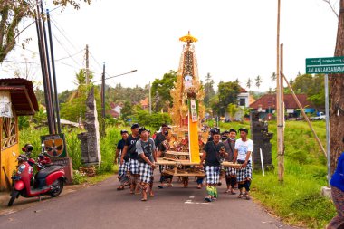 Bali adasında bir cenaze töreni. Geleneksel renkli kıyafetler giyen insanlar mücevher takıp yakılmak için bir ceset taktılar. Bali, Endonezya - 12.11.2022
