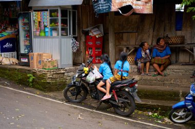 Çocuklar Asya 'da bir köyde kasksız bir şekilde scooter' a biniyorlar. Bali, Endonezya - 12.24.2022