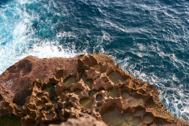 Güneş batarken bir okyanus dalgası dokulu bir kayaya çarpıyor.