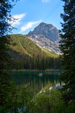 İnanılmaz güzel şeffaf zümrüt göl. Kara Prens Sirk Yolu 'ndaki kayalık dağın yansıması. Güneşli yaz gününde Alberta, Kananaskis 'te kar yağan görkemli Kanada dağları.