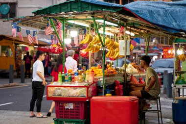 Küçük taze bir meyve dükkanının satıcısı Malezya sokaklarında çalışıyor. Kuala Lumpur, Malezya - 11.15.2022