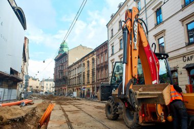 Avrupa 'nın eski sokaklarında kanalizasyon ve su onarımı. Eski boruları yenileriyle değiştirmek için kazılmış bir yolda bir kazıcı duruyor. Krakow, Polonya - 05.16.2019