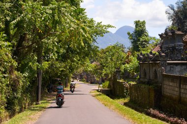 Bir motosikletli Asya 'da manzaralı asfalt bir yolda gidiyor. Bali, Endonezya - 12.10.2022