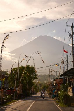 Köyde tatil için dekore edilmiş yol volkanının manzarası. Yol boyunca bambu süslemeleri. Gün batımından önce Agung Dağı 'nın bulutlarla kaplı bir manzarası. Bali, Endonezya - 12.10.2022