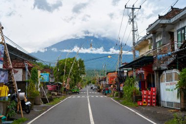 Köyde tatil için dekore edilmiş yol volkanının manzarası. Yol boyunca bambu süslemeleri. Agung Dağı 'nın bulutlarla kaplı bir manzarası. Bali, Endonezya - 12.24.2022