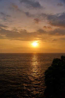 Gün batımında dağ ve okyanus manzarası. Denizin üzerinde güneşli bir yol