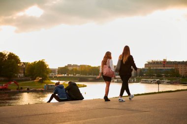 İnsanlar yazın gün batımında rahatlar ve rıhtım boyunca yürürler. Krakow, Polonya - 05.16.2019