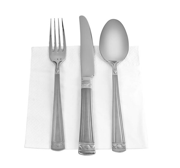 Концепция питания. Три кухонных принадлежностей. Вилка, нож и ложка на столе салфетка изолированы на белом фоне