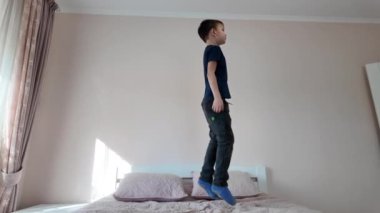 Neşeli çocuk yumuşak bir yatakta zıplayarak eğleniyor.